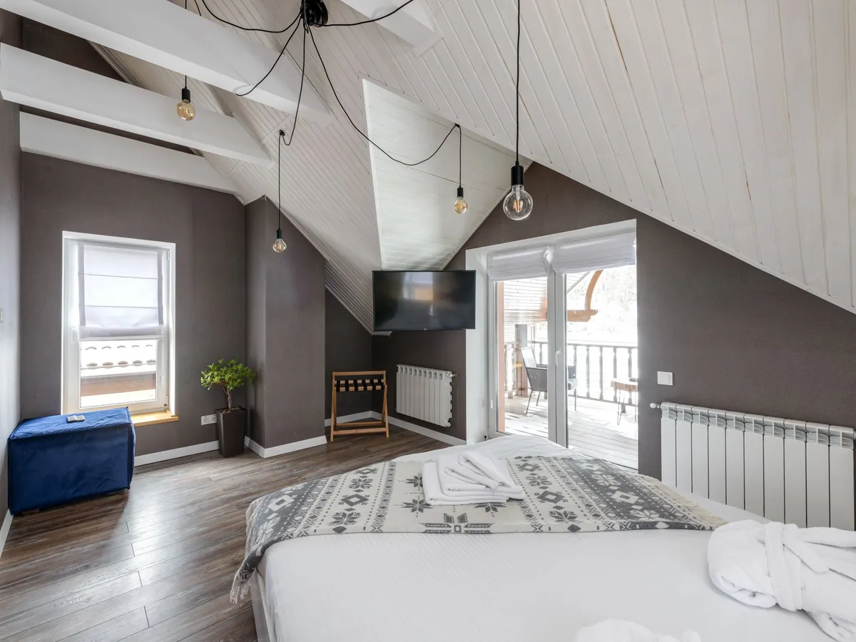 Helles Schlafzimmer unter dem Dach mit Doppelbett, Fenster und Balkontür