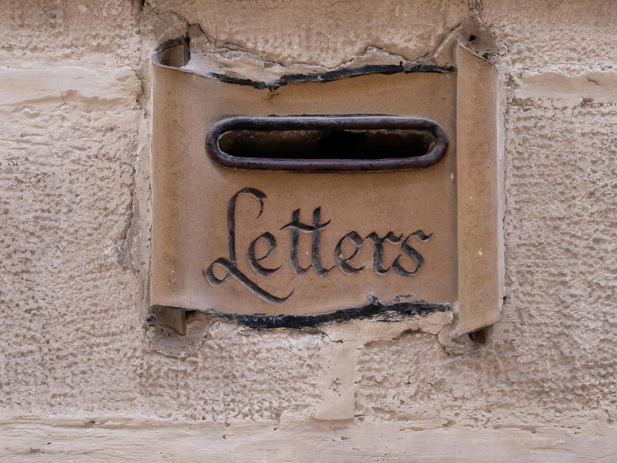 Alter Briefkastenschlitz mit der Aufschrift Letters in einer Steinmauer